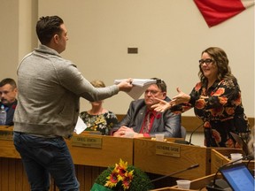 Eric Bell, spokesperson for Queen City for All, hands a petition to Regina Public Schools board chair Katherine Gagne, calling for her resignation and asking the board to reconsider a motion to "recognize and support" Pride week and fly the Pride flag for a week every June. The petition was presented during a board meeting at the board's office in October.