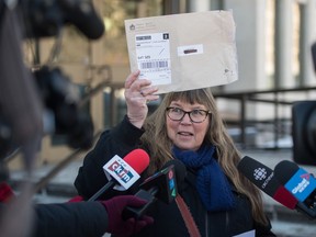 Patricia Elliott, a professor at the University of Regina, speaks to media at the front of Regina's Court of Queen's Bench regarding her legal challenges in accessing information. She is pictured holding up an envelope sent to her by the government containing documents she requested.