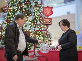 Red Cross volunteer Corey Nissen, left, is the first to put money into the 2019 Christmas Kettle Campaign in Regina.