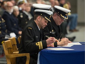 Incoming commanding officer of HMCS Queen LCdr Clark Northey, left, signs change of command documents as he takes over for outgoing commanding officer LCdr Trent Nichols, right, during a change of command ceremony held their building on Navy Way.