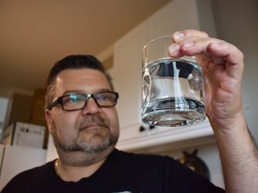 Mike Susylinksi inspects a glass of water filled from the freestanding water dispensar at his home in Regina, SK. He does not drink the water that flows from his kitchen tap.