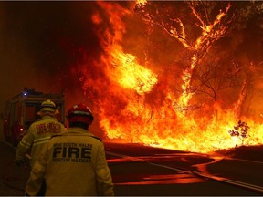 Fire and Rescue personal run to move their truck as a bushfire burns next to a major road and homes on the outskirts of the town of Bilpin on December 19, 2019 in Sydney, Australia. NSW Premier Gladys Berejiklian has declared a state of emergency for the next seven days with ongoing dangerous fire conditions and almost 100 bushfires burning across the state. It's the second state of emergency declared in NSW since the start of the bushfire season.