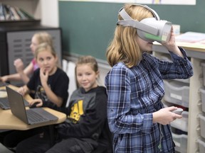 Claire Marshall, Grade 5 student at St. Angela Merici Elementary School, tries on a pair of VR goggles while working on their coding project in their classroom.