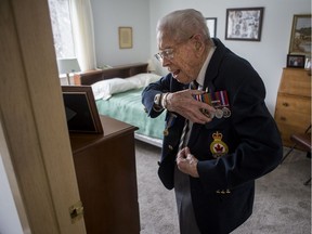 Bob Atkinson, a 95-year-old Second World War veteran who just received an award for his 75 years of service with the Royal Canadian Legion, attaches his medals to his legion jacket at his home in Saskatoon on  Nov. 28, 2019.