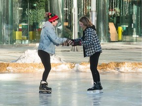 Jayde Richter, left, skates with Skyla Roulston on a rink made next to Victoria Park in Regina, Saskatchewan on Dec. 27, 2019.