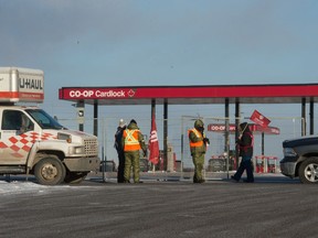 Picketing Unifor members and security guards walk next to a fence erected as part of a blockade which blocked access to the Co-op cardlock location and the Federated Co-operatives Limited (FCL) office on the northeast end of Regina, Saskatchewan on Jan 10, 2020. On Monday, a similar blockade was set up in Weyburn.