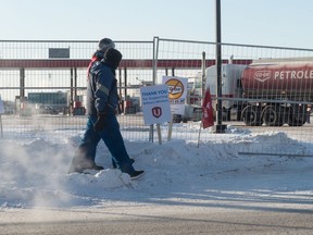 Picketing Unifor members walk next to a fence erected as part of a blockade which blocked access to the Co-op cardlock location and the Federated Co-operatives Limited (FCL) office on East Turvey Road in Regina, Saskatchewan on Jan 10, 2020.