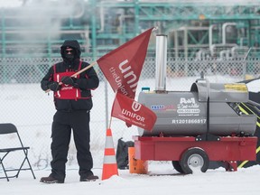 A picketer stands near a large, portable heater during a day where temperatures hovered near -30C outside the Co-op Refinery Complex in Regina, Saskatchewan on Jan. 14, 2020.