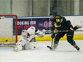 The University of Regina Cougars' Shaelyn Valloton, right, puts the puck past University of Manitoba Bisons netminder Erin Fargey  in Canada West women's hockey action Saturday at the Co-operators Centre.