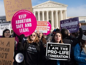 In this file photo taken on January 18, 2019 pro-choice activists hold signs alongside anti-abortion activists participating in the "March for Life," an annual event to mark the anniversary of the 1973 Supreme Court case Roe v. Wade, which legalized abortion in the US, outside the US Supreme Court in Washington, DC.