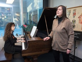 Katherine Dowling, left, plays piano while Helen Pridmore sings in Pridmore's office at the University of Regina.