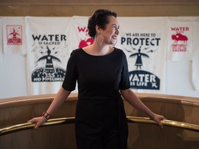 Felicia Gay, a curatorial fellow with the MacKenzie Art Gallery, stands in front of protest posters designed by Christi Belcourt.