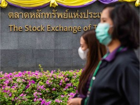 People wearing face masks walk past the Stock Exchange of Thailand on Feb. 28, in Bangkok. Fearing the spread of Covid-19, a new strain of coronavirus originating in Wuhan, China, stock markets have suffered across the globe.