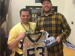 Winnipeg Blue Bombers offensive lineman Patrick Neufeld is shown with LIT tournament director Troy Casper at the Luther Invitational Tournament on Thursday at the Semple Gymnasium. Neufeld, a Luther grad, presented his old school with a game-worn Blue Bombers jersey and a 2019 Grey Cup hat, both of which he autographed.