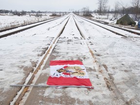 A Canadian maple leaf flag with native symbols on it lays on the train tracks in Tyendinaga Mohawk Territory, near Belleville, Ont., on Tuesday, Feb. 11, 2020.