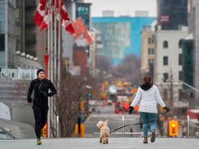 A jogger keeps his distance from a woman walking her dog in downtown Toronto, Ontario on March 24, 2020.