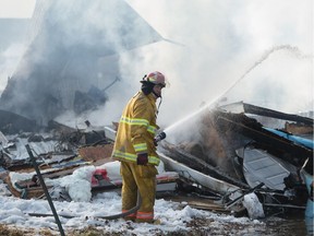 A firefighter works to douse a smouldering fire at a property in Pense, Saskatchewan on Mar. 6, 2020.