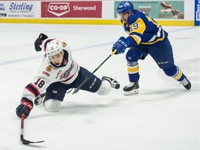 The Regina Pats' Cole Dubinsky reaches for the puck while being pursued by the Saskatoon Blades' Zach Huber (19) on March 7.