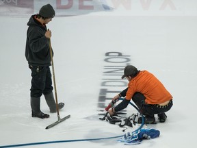 Evraz Place employees remove logos from the ice surface at the Brandt Centre in Regina Tuesday.