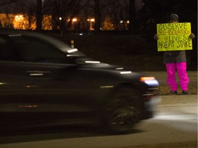 Amid the COVID-19 virus outbreak, France Watters holds a sign urging people to observe social isolation practices as they leave the Regina International Airport in Regina, Saskatchewan on Mar. 21, 2020.