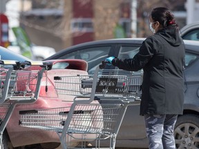 A person wearing rubber gloves and a surgical mask during the COVID-19 pandemic returns a shopping cart at a grocery store in Regina on March 26, 2020.