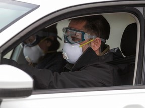 Two men wearing masks drive up for assessment as the city's public health unit holds walk-in testing for coronavirus disease (COVID-19) in Montreal, Quebec, March 23, 2020.
