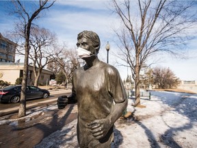 As the number or COVID-19 cases increase in Saskatchewan, a medical mask is seen on the statue of community volunteer, radio host and Order of Canada recipient Denny Carr in downtown Saskatoon.