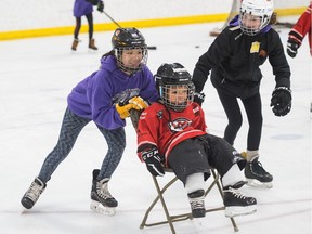 Kaitlyn Mah, left, and Kiera Ackerman, right, of the Regina Rebels pee wee B female hockey team skate with Blake Dussion of the Super HEROS hockey program at the Doug Wickenheiser Arena.