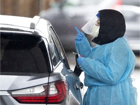 A health care worker gives instructions to a patient as she carries out drive-through tests for COVID-19 at an installation in Côte-St-Luc on Monday, March 30, 2020.