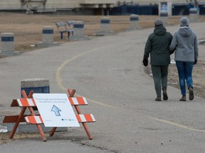 Two people walk together on the pathway around Wascana Lake on Saturday. Wascana's blue trail is now designated a one-way path to deal with concerns about the transmission of COVID-19.