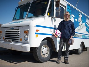 Milkman Kevin Ramstead stands holding milk products in front of one of his delivery trucks on the northwest side of Regina, Saskatchewan on April 9, 2020. Ramstead says he's the city's only remaining door-to-door milkman, but his customer base has recently expanded.