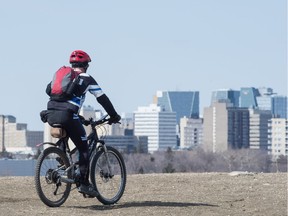 A cyclist looks out at the view of the city while riding on Douglas Park hill on a sunny spring day in Regina, Saskatchewan on April 14, 2020.