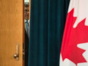 Saskatchewan Premier Scott Moe looks at the camera through a a partially open door prior to unveiling his government's plan to re-open the province's economy at a news conference held at the Saskatchewan Legislative Building in Regina, Saskatchewan on April 23, 2020.
