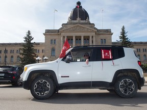 A Unifor member drives an automobile past the Saskatchewan Legislative Building as part of a "vehicle rally" for the union taking place in Regina, Saskatchewan on April 29, 2020. The rally was in support of Unifor Local 594, the members of which are currently locked out of the Co-op Refinery Complex.
