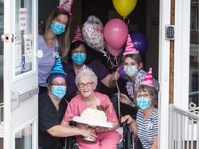 Kay Shropshire, centre, is surrounded by staff members of the William Booth Special Care Home, as she celebrates her 100th birthday at the home in Regina, Saskatchewan on April 30, 2020.