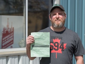 REGINA, SASK : May 5, 2020  -- Aaron Marshall, a Unifor Local 594 member, holds a ticket he was issued for taking part in parade without a permit. He is pictured standing out side the Unifor union hall on Hodsman Road in Regina, Saskatchewan on May 5, 2020. He was part of a large parade of union members in vehicles, which honked as they drove past various buildings, including the Saskatchewan Legislative Building and the Regina Police Service headquarters. BRANDON HARDER/ Regina Leader-Post