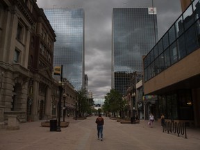 A woman walks down the centre of Scarth Street beneath a cloudy sky in Regina, Saskatchewan on May 26, 2020.