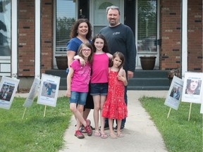 Twyla and Chris McDougall stand in their front yard with their three daughters (from left) Soleil, Emmanuella and Allegra McDougall in Regina on May 27, 2020. They are surrounded by lawn signs bearing the images of "CF warriors." Emmanuella was born with cystic fibrosis and, as a result, the family has long been accustomed to wearing masks and avoiding people who are sick.