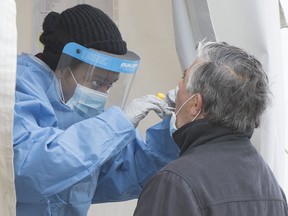 A health-care worker swabs a man at a walk-in COVID-19 test clinic in Montreal North, Sunday, May 10, 2020, as the COVID-19 pandemic continues in Canada and around the world.