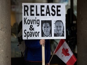A young man holds a sign bearing photographs of Michael Kovrig and Michael Spavor, who have been detained in China for more than a year, outside the B.C. Supreme Court, where Huawei chief financial officer Meng Wanzhou was attending a hearing, in Vancouver, on Jan. 21.