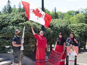 One person waves a flag while others stand by during at a rally for missing and murdered Indigenous women held at the Saskatchewan Legislative building on June 5, 2020.