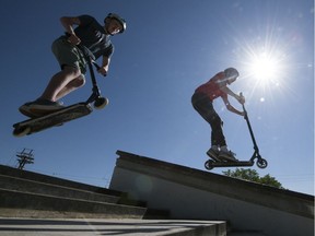 Mitchell Saxby, left, and Levi Rempel fly through the air on their scooters at the Wascana Skateboard Plaza in Regina on Friday, June 12, 2020, the first day city outdoor recreation spaces reopened.
