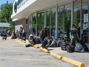 People wait with bags of recycling at the SARCAN location on Grant Road in Regina, Saskatchewan on June 15, 2020. The recycling depot is now open, but has enacted social distancing measures due to the COVID-19 pandemic.
