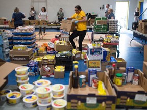 Laura Anaka, in yellow, gathers food items to be placed into hampers as part of a nutrition program being run out of Archbishop M.C. O'Neill Catholic High School in Regina, Saskatchewan on June 16, 2020.