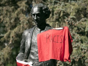 The John A. Macdonald statue in Victoria Park is covered in protest flags in Regina on Friday, July 3, 2020.