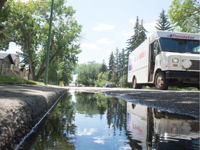 A Purolator courier truck drives up Athol Street in Regina, Saskatchewan on July 27, 2020. Water can be seen laying in the gutter on one side of the road. The street is one of a number of streets in North Central Regina that will have their storm sewer infrastructure upgraded as part of the $15-million North Central Drainage Project to help prevent flooding and ponding.