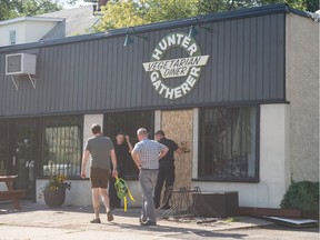A fire occurred at the Hunter Gatherer Vegetarian Diner, pictured here in Regina, Sask. on July 30, 2020. An employee of the Regina Fire Department is seen here removing a board from the front door of the building.