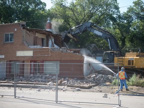 A crew works to demolish a damaged building on 11th Avenue in Regina, Saskatchewan on July 31, 2020. A fence surrounding the building, to protect pedestrians from falling debris, was blocking 11th Avenue and the demolition of the building should mean the street can be reopened.