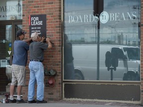 Two men put up a for lease sign on the Boards and Beans cafe in Regina, Saskatchewan on July 14, 2020. The cafe will be permanently closing due to a lack of business brought on by the COVID-19 pandemic.