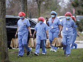 Healthcare workers wearing protective gear carry meals provided by Maple Leaf Sports & Entertainment.